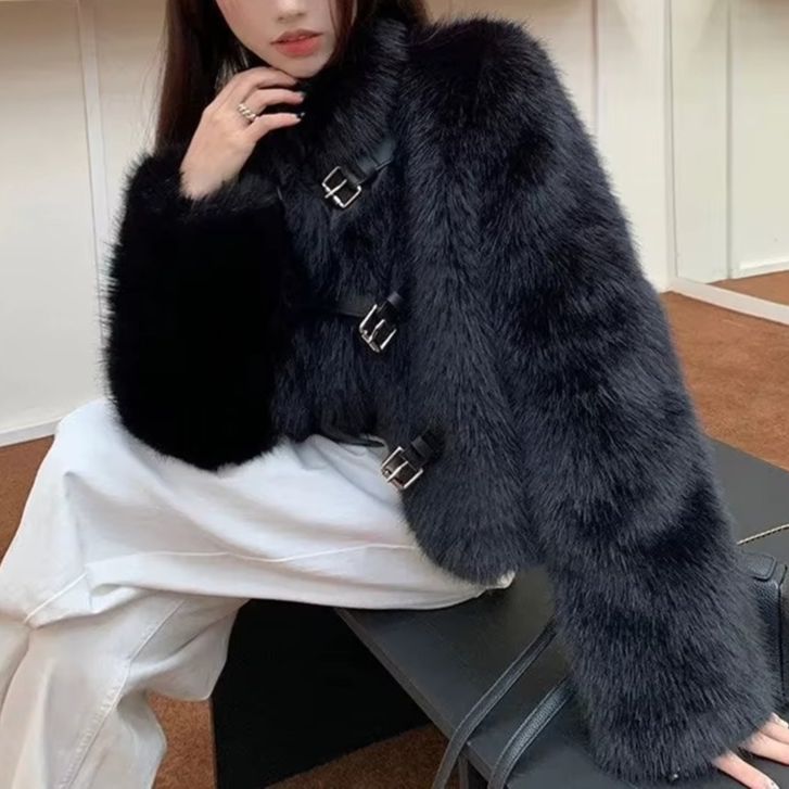 Person wearing a black fur coat sitting on a chair indoors.