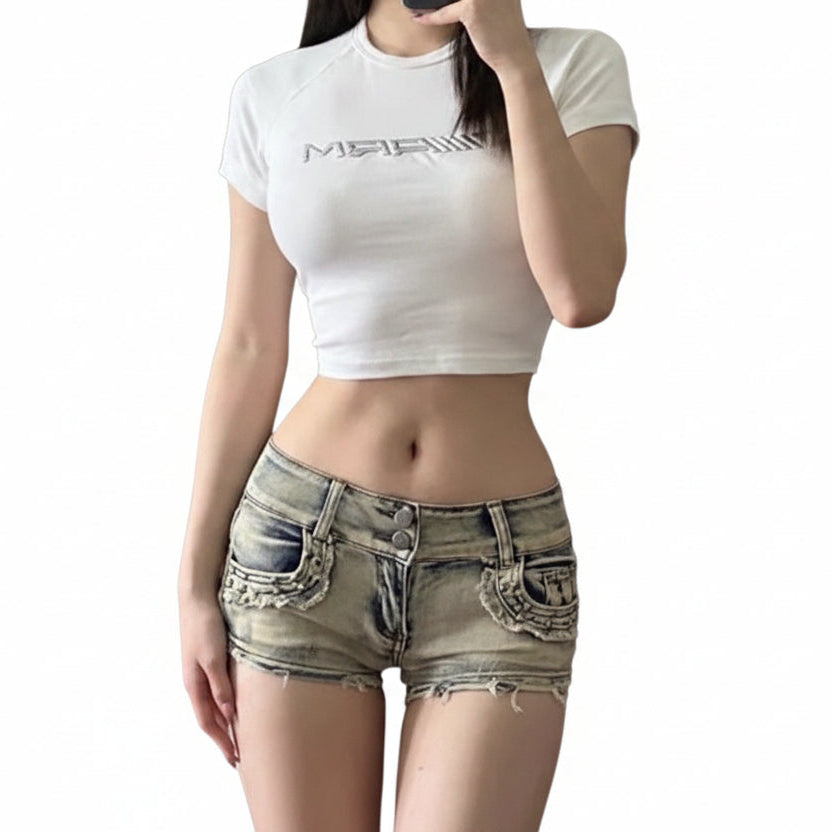 A person wearing a white crop top and low waist denim shorts with a frayed hem.