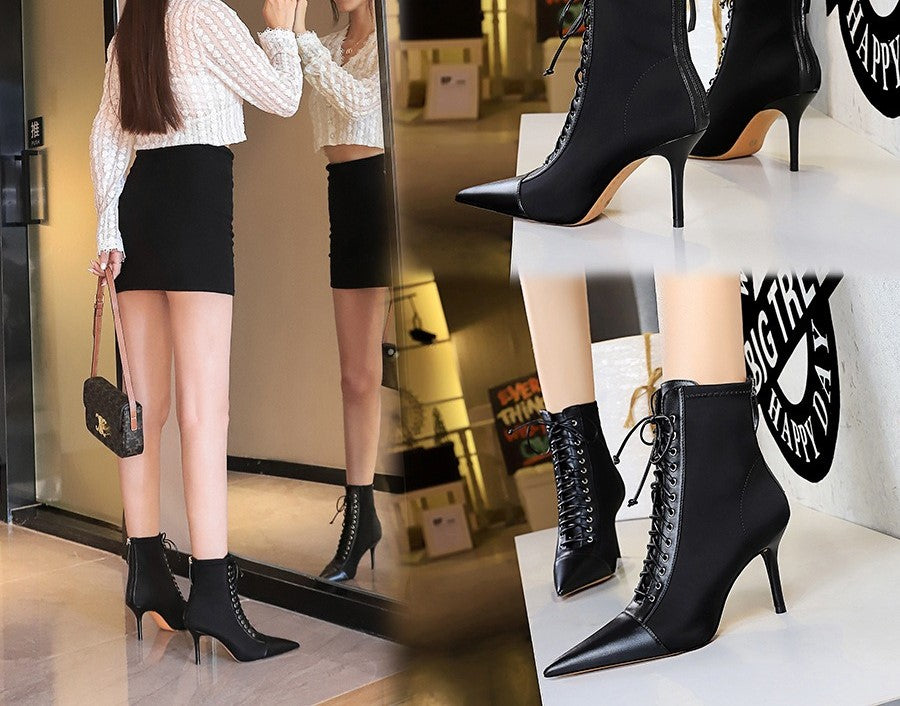 Black high-heeled lace-up boots being worn and displayed in a store setting.