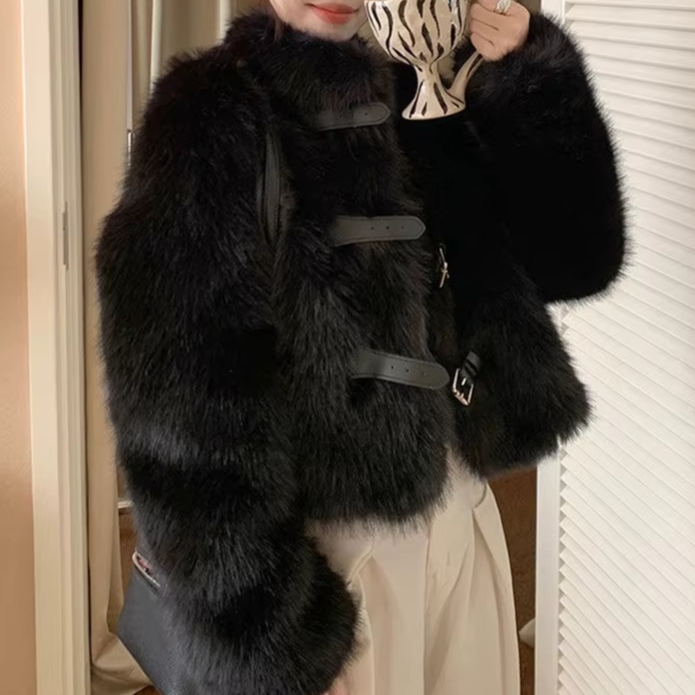 Person wearing a black fur coat holding a patterned cup.