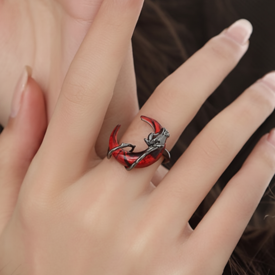 Close-up of a hand wearing a red and silver ring with a detailed design.